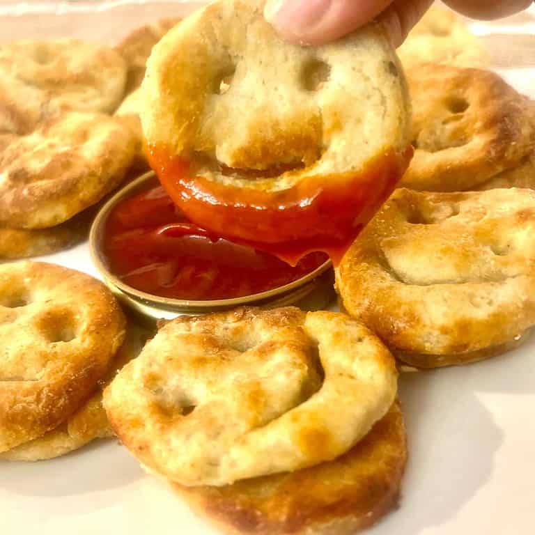 A hand holding a homemade from scratch smiley fry dipped in ketchup that was made in the airfryer